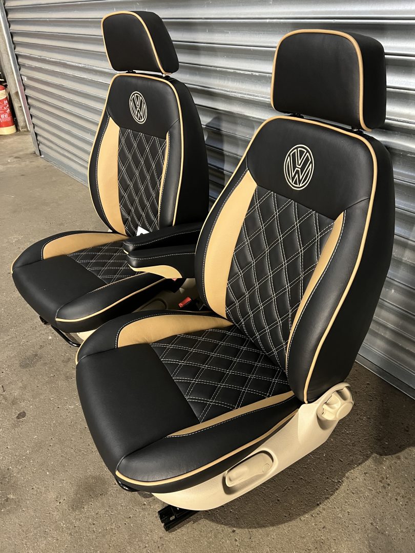 Pair of MK1 Swivel Replacement Captain Seats, side-angled view showing beige inserts, Bentley stitch pattern, beige piping, and VW logos on matt black leatherette.