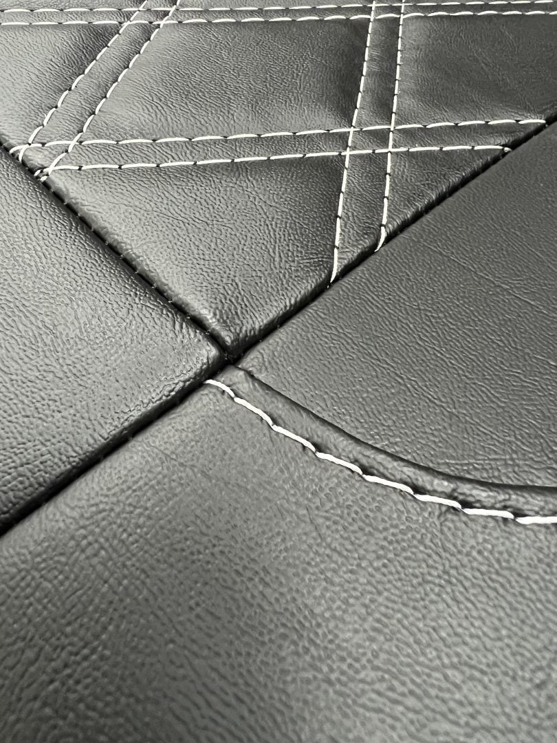 Rock and roll bed full width 3 seater M1 tested gas assisted Legged, close up of black leatherette with grey stitching.