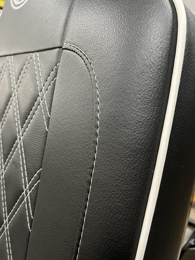 Rock and roll bed full width M1 tested gas assisted legged, close-up of the backrest in black faux Leather with white stitching and piping.
