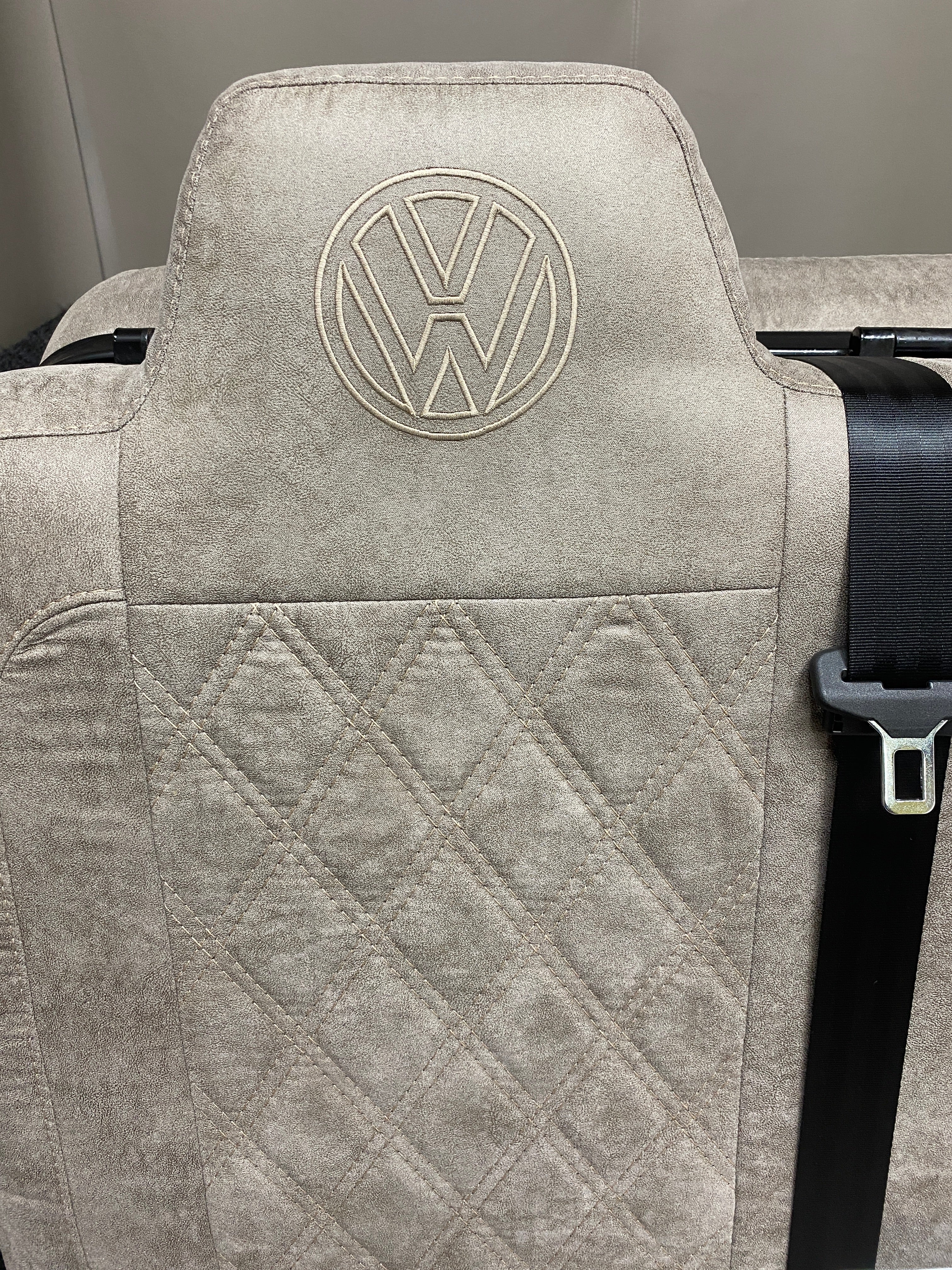 Rock & Roll Bed M1 Tested 3/4 Width, close-up of upper backrest in beige faux suede with Bentley stitching and embroidered VW logo.