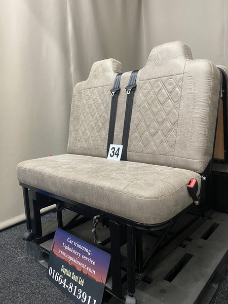 Rock & Roll Bed M1 Tested 3/4 Width, side view of beige faux suede seat with Bentley stitching, VW logos, seatbelts and black metal frame.
