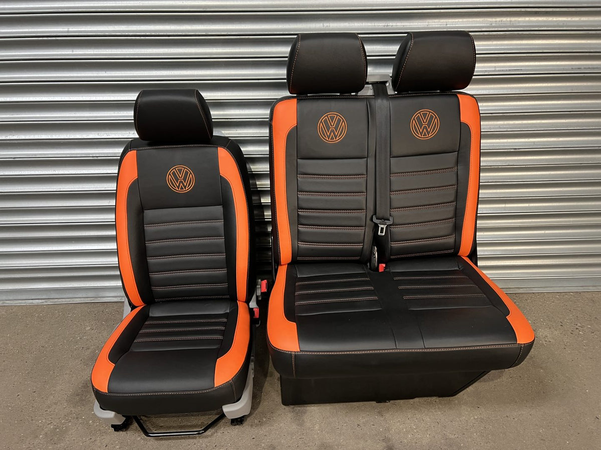 VW T5 T6 front seats in black leatherette upholstery with orange edges, black horizontal stitching and orange VW logos.
