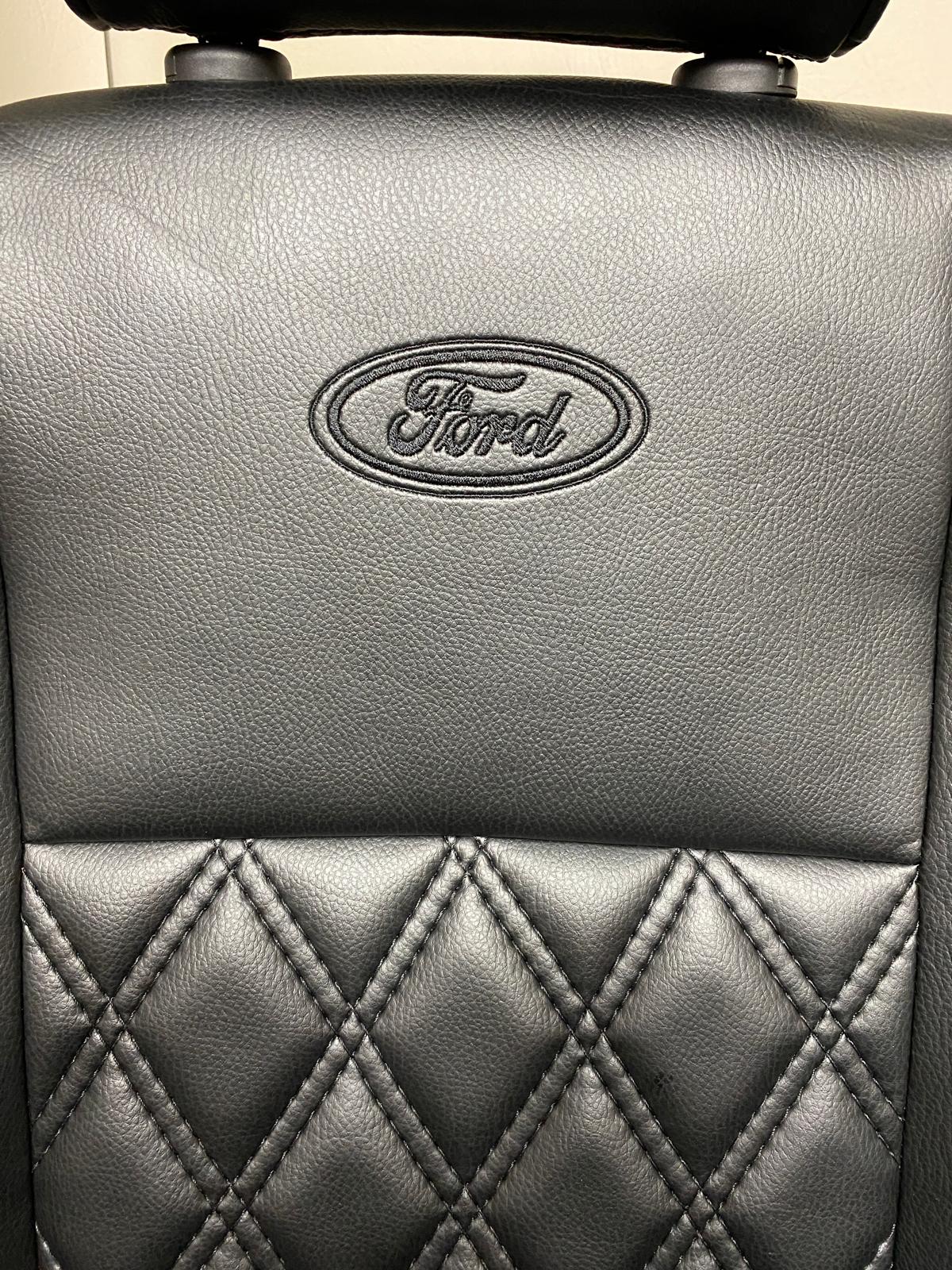 Close-up of Ford Transit Custom Front Seat showcasing the Ford logo on black leatherette and Bentley diamond stitch pattern.
