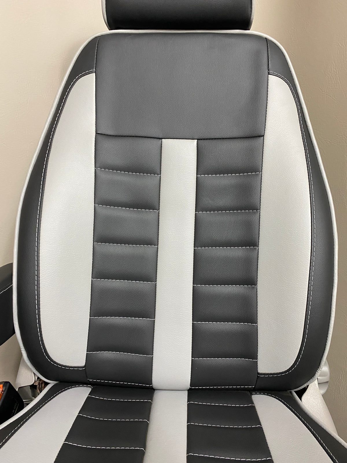 MK1 Replacement Swivel Captain Seat close-up of seat back with wide horizontal stitching, grey leatherette inserts, and white piping on black leatherette.