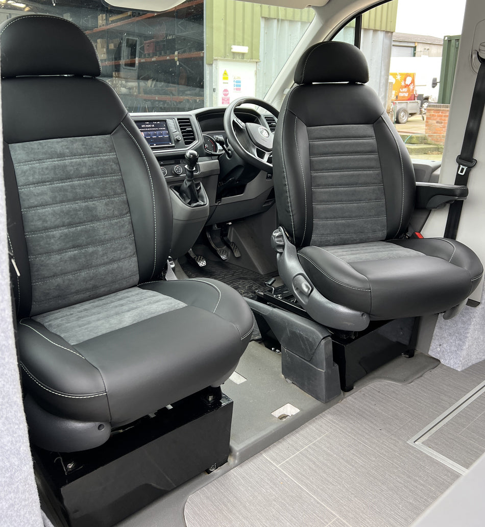 Pair of MK 2 Replacement Swivel Captain Seats, angled view of matt black leatherette with dark grey faux suede centre panels and horizontal stitching.
