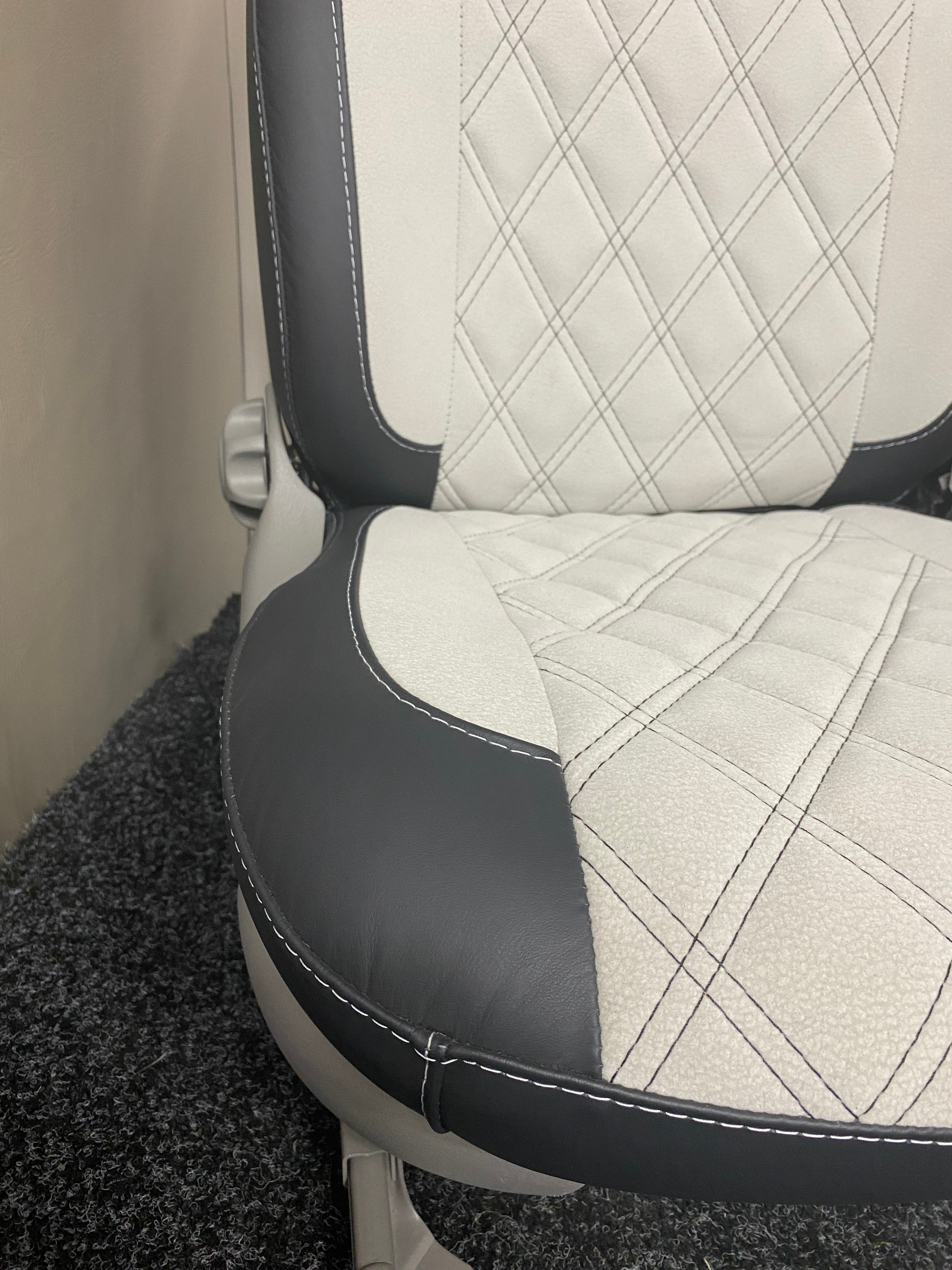 MK1 Replacement Captain Swivel Seat, close-up, showcasing the black leatherette edge panel and white microfibre centre panel with Bentley cross stitch pattern.