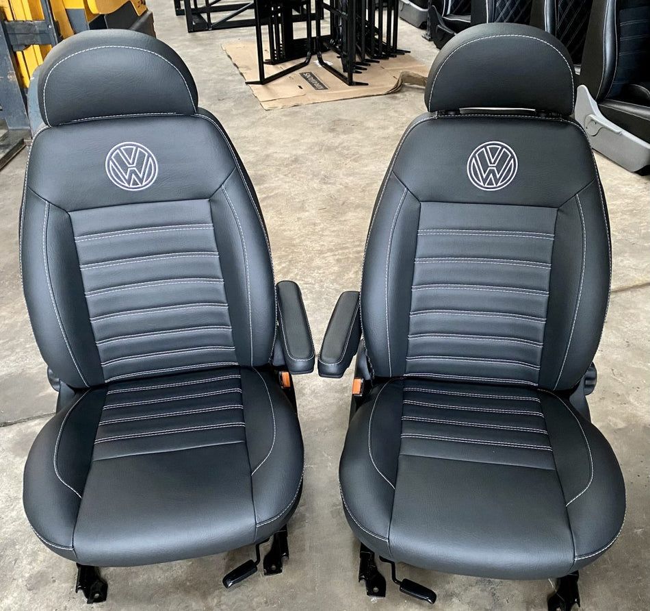 Pair of VW T4 T5 T6 Crafter - MK2 Replacement Swivel Captain Seats in matt black leatherette with horizontal white stitch pattern and VW logos.