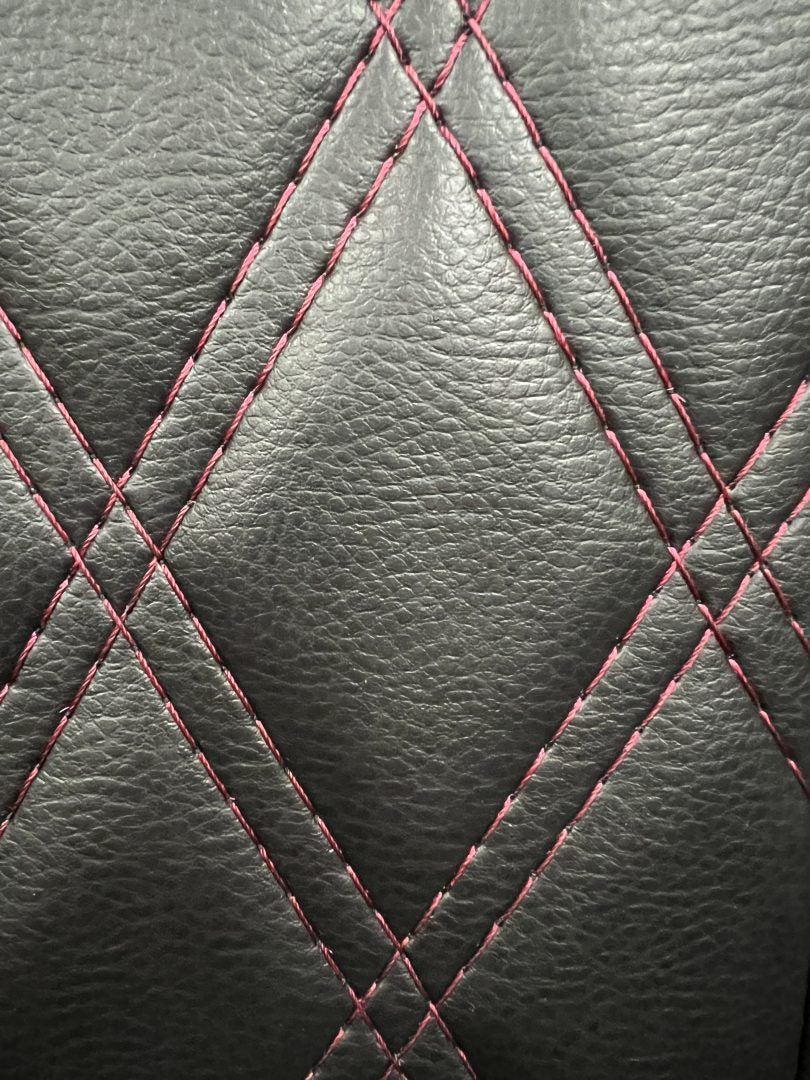 Rock and roll bed full width M1 tested gas assisted legged, close-up of the black leather with Burgundy stitch pattern.