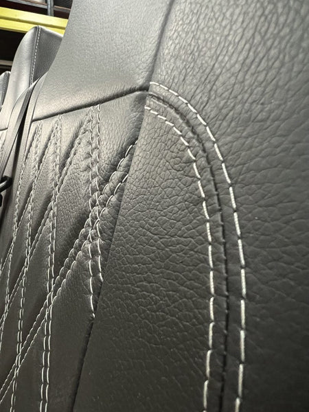 Rock and roll bed full width M1 tested gas assisted legged, close-up of the seat back in black leather with light grey Bentley stitch pattern.