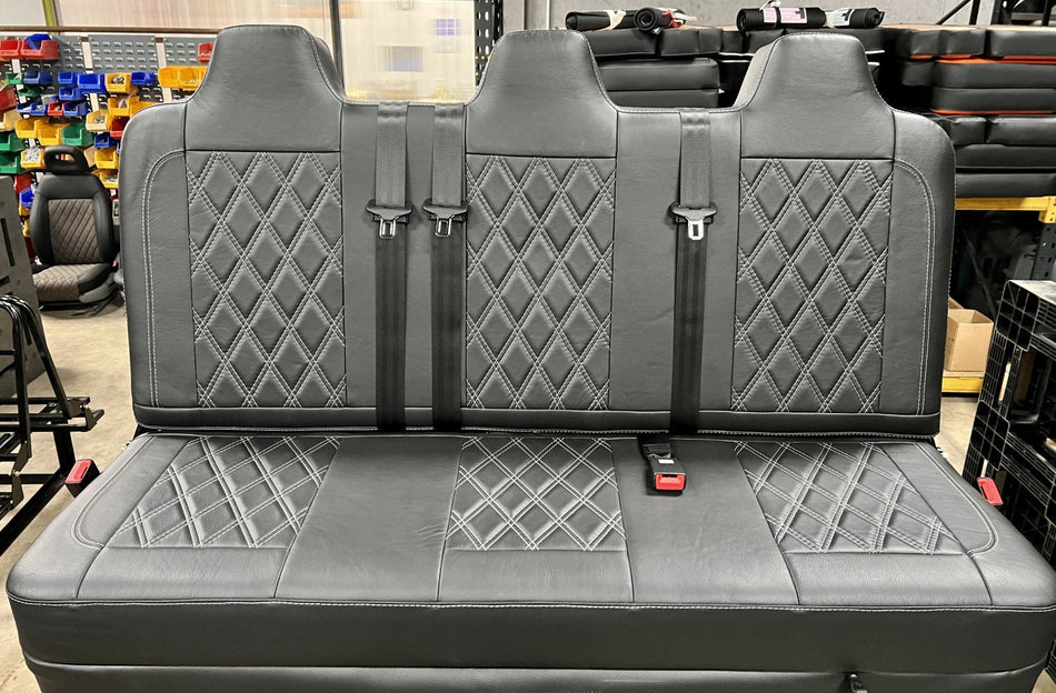 Rock and roll bed full width M1 tested gas assisted legged in black leather upholstery with light grey Bentley stitching and integrated black seatbelts.