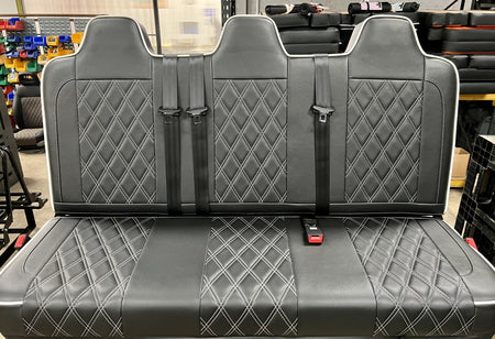 Rock and roll bed full width M1 tested gas assisted legged in black leatherette upholstery with white Bentley cross stitching, piping and integrated seatbelts.