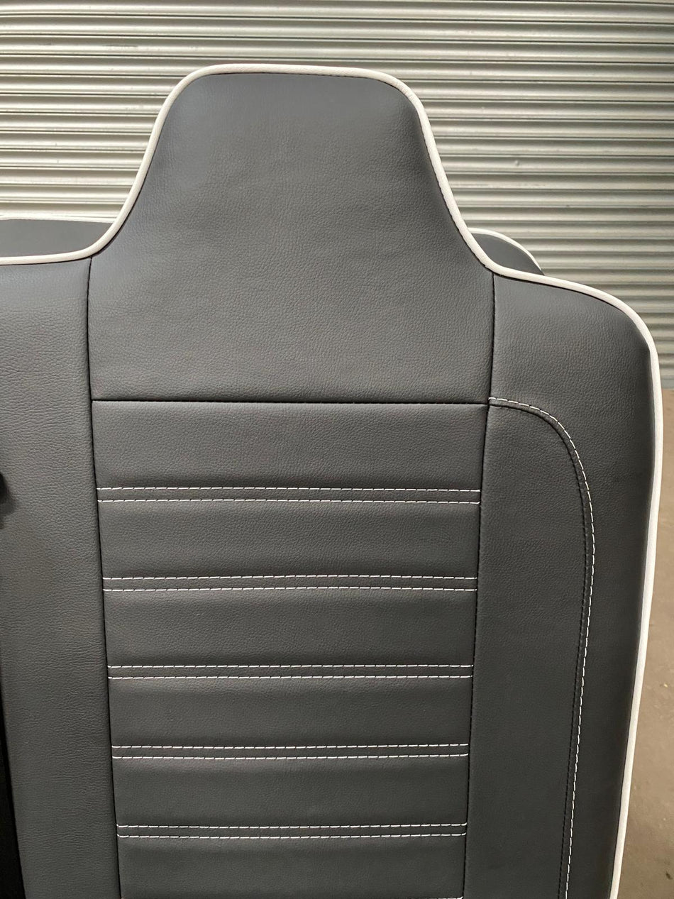 Rock and Roll Bed, Gas Assisted Full Width Legless M1 close-up of black leatherette backrest with white piping and horizontal stitching.
