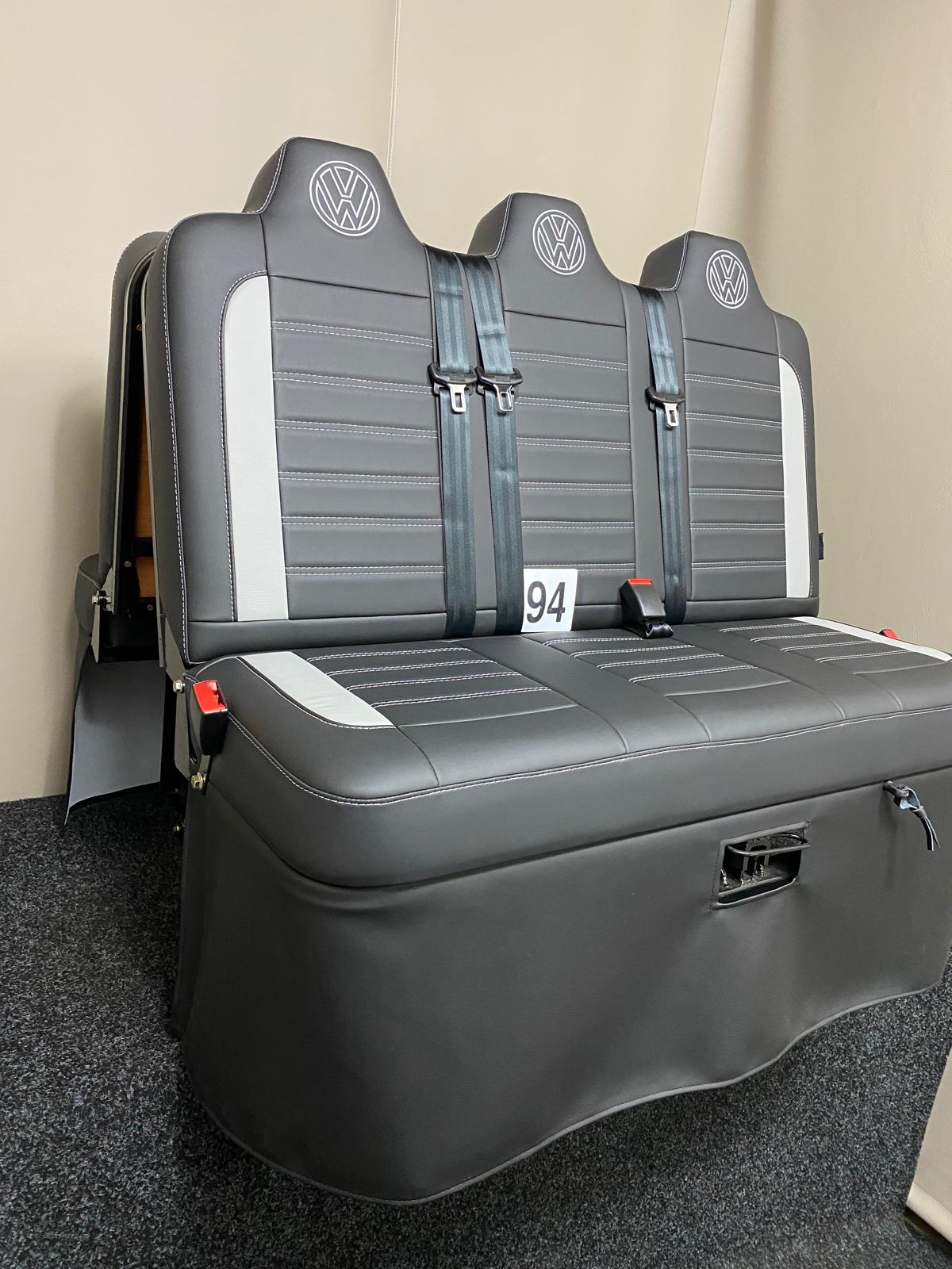 Rock and roll bed Three Seater-gas assisted leisure-120 cm in black leatherette with light grey inserts, light grey Bentley cross stitching, and VW logos on the headrests, from a slightly angled side view.