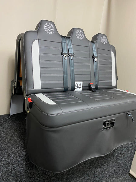 Rock and roll bed Three Seater-gas assisted leisure-120 cm in black leatherette with light grey inserts, light grey Bentley cross stitching, and VW logos on the headrests, from a slightly angled side view.