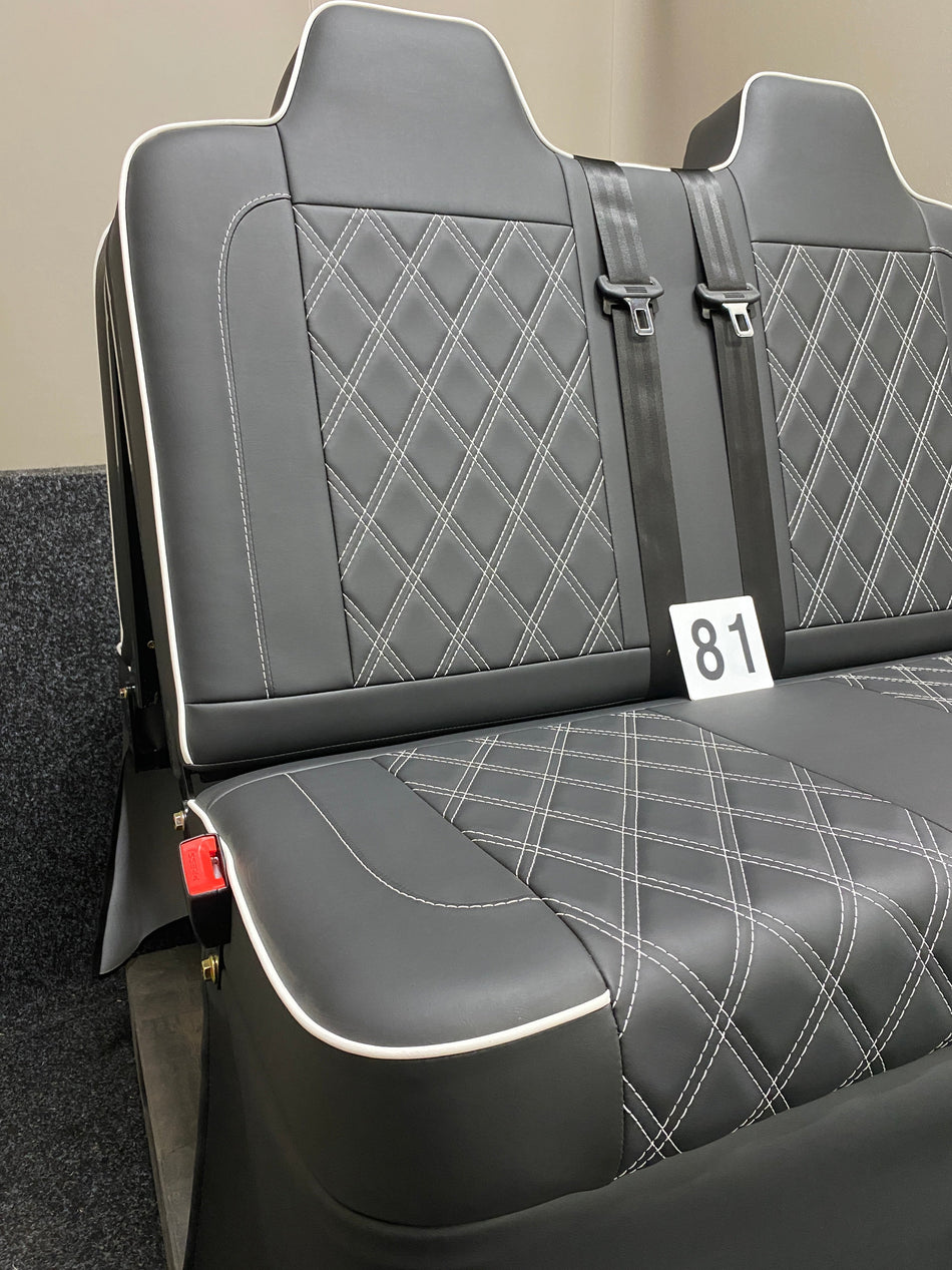 Rock & Roll Bed 3/4 M1 Tested 2 Seater, angled front view of black leatherette seat with white piping, Bentley cross stitching and seatbelts. 