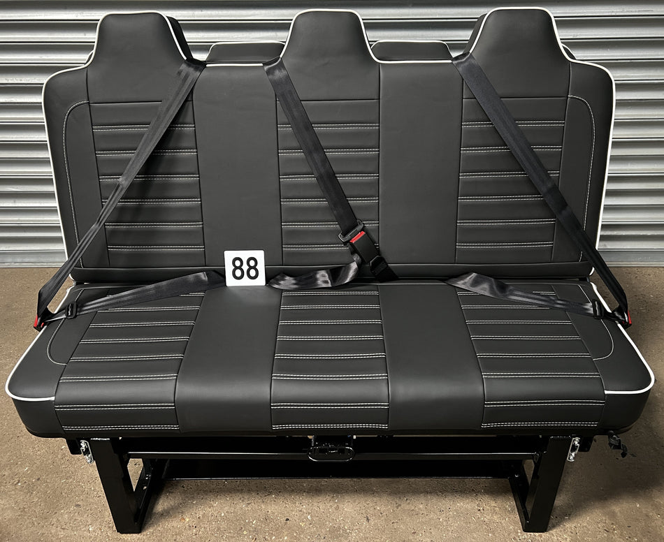 Rock & Roll Bed Full Size M1 Tested Deluxe – Legless Gas Assisted, front view with black seatbelts, white piping, and horizontal white stitching on black leatherette.