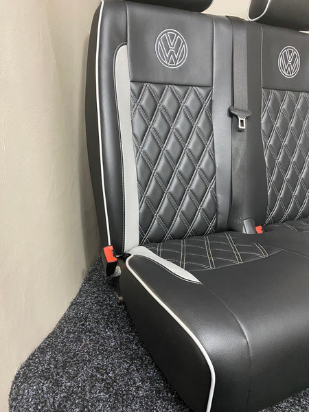Volkswagen Crafter double front seat, angled view of black leatherette with grey inserts and piping, featuring light grey Bentley stitching and white VW logos.