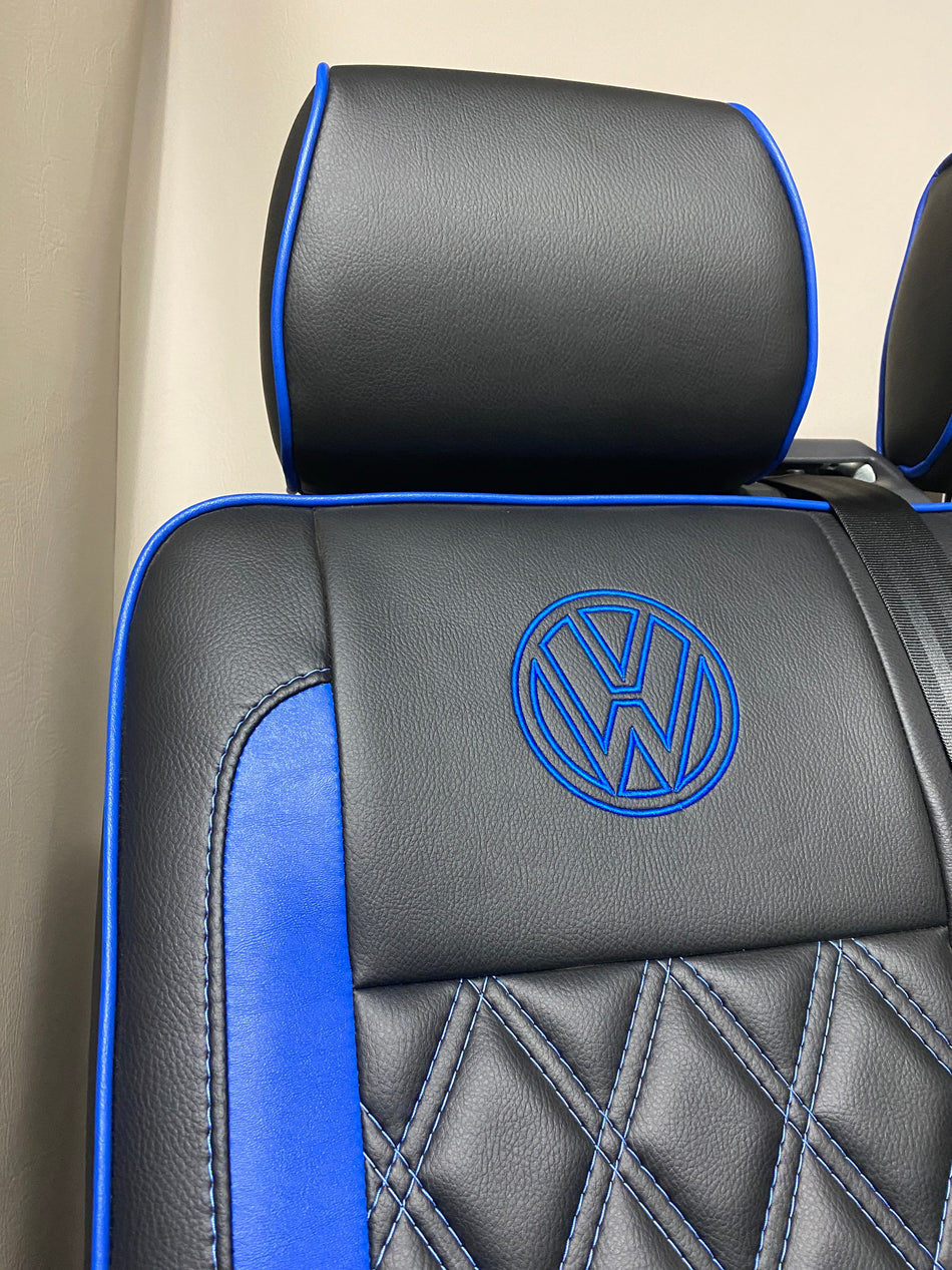 VW Factory Front Seats T5 T6, close-up of blue VW logo on black leatherette seat back with blue piping and blue Bentley cross stitching.