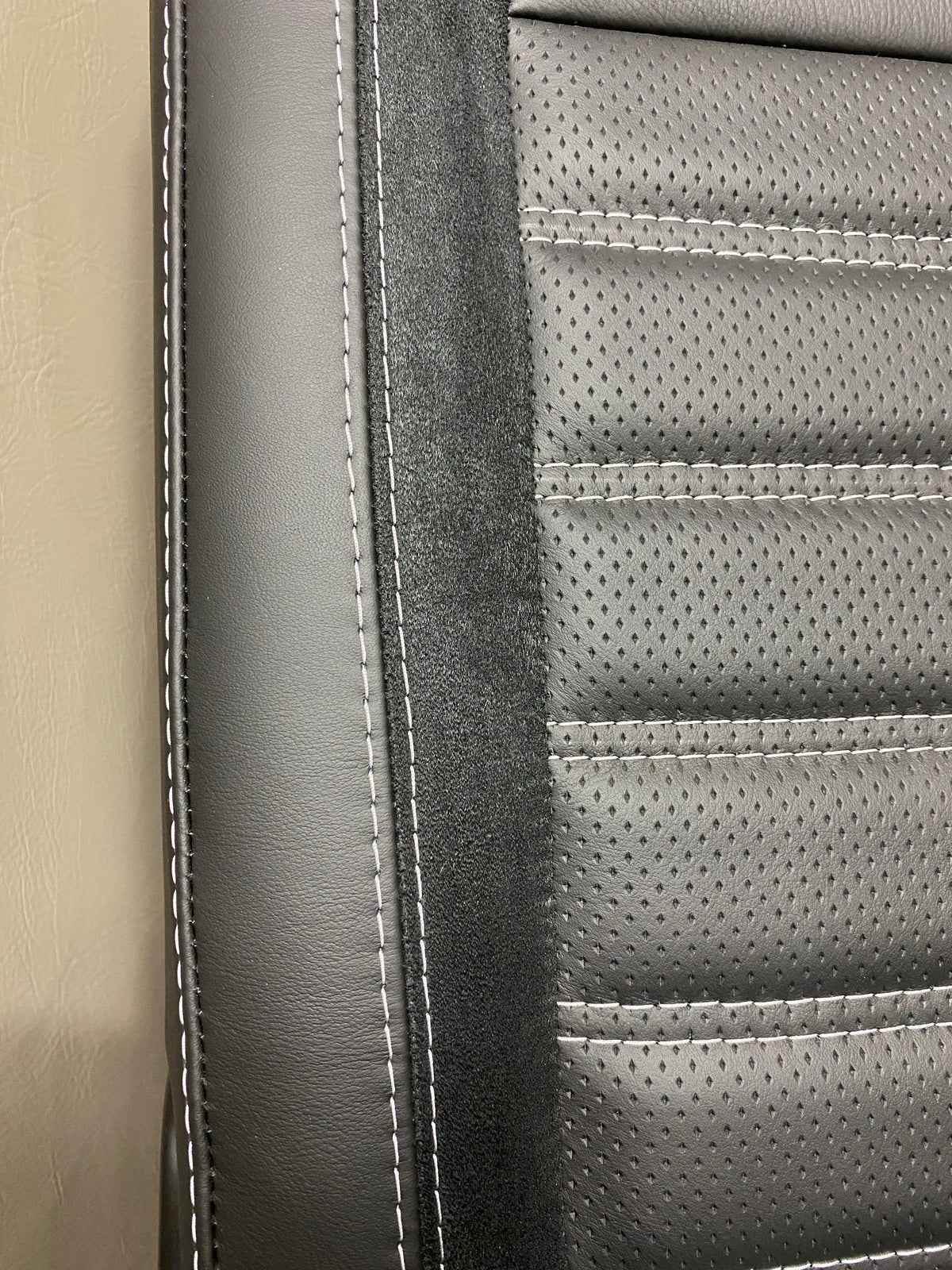VW Factory T5 T6 seat close-up of black real leather side panel with Alcantara faux suede insert and perforated centre panel featuring black horizontal wide cross-stitching.