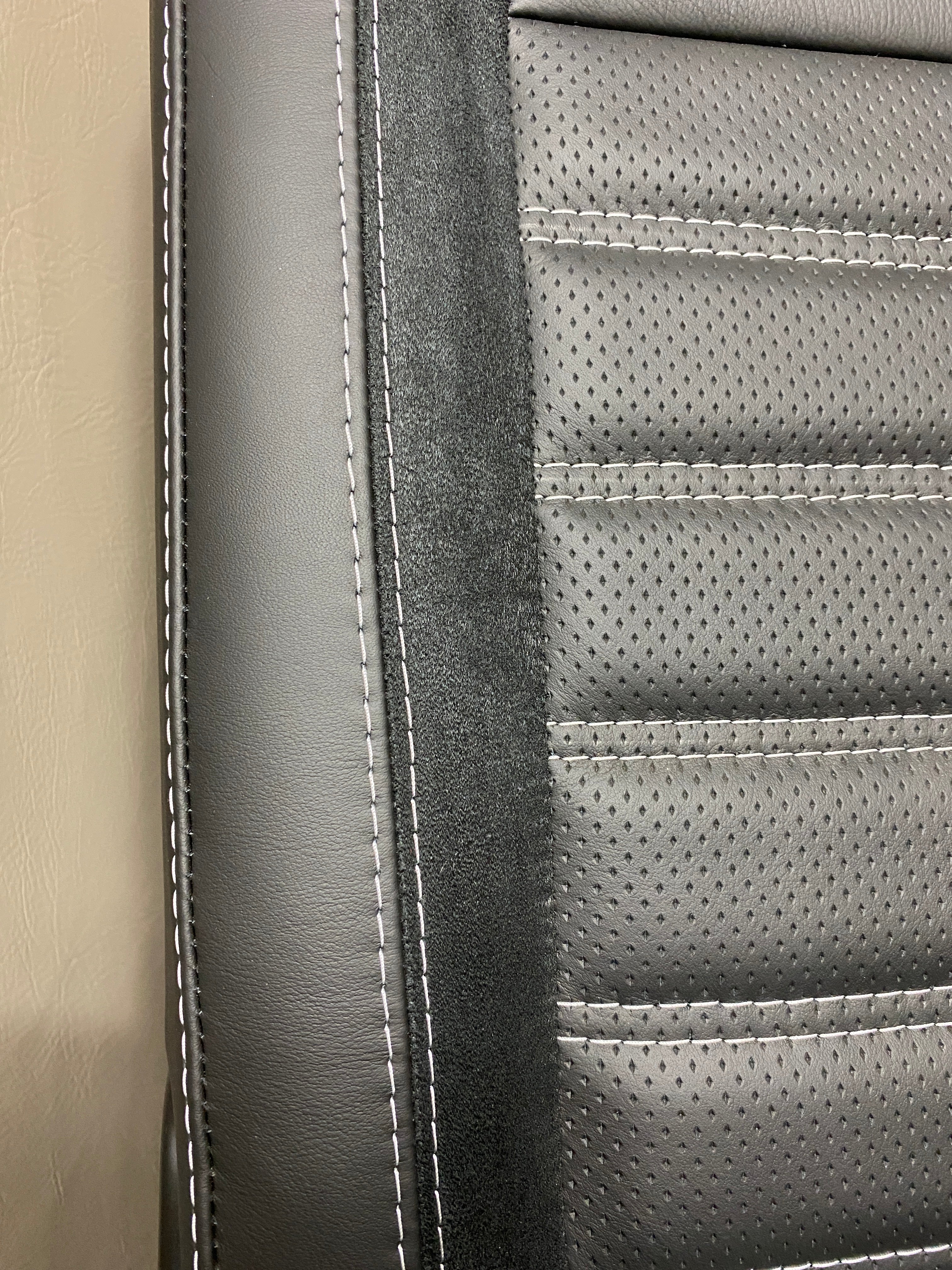 VW Factory T5 T6 seat close-up of black real leather side panel with Alcantara faux suede insert and perforated centre panel featuring black horizontal wide cross-stitching.