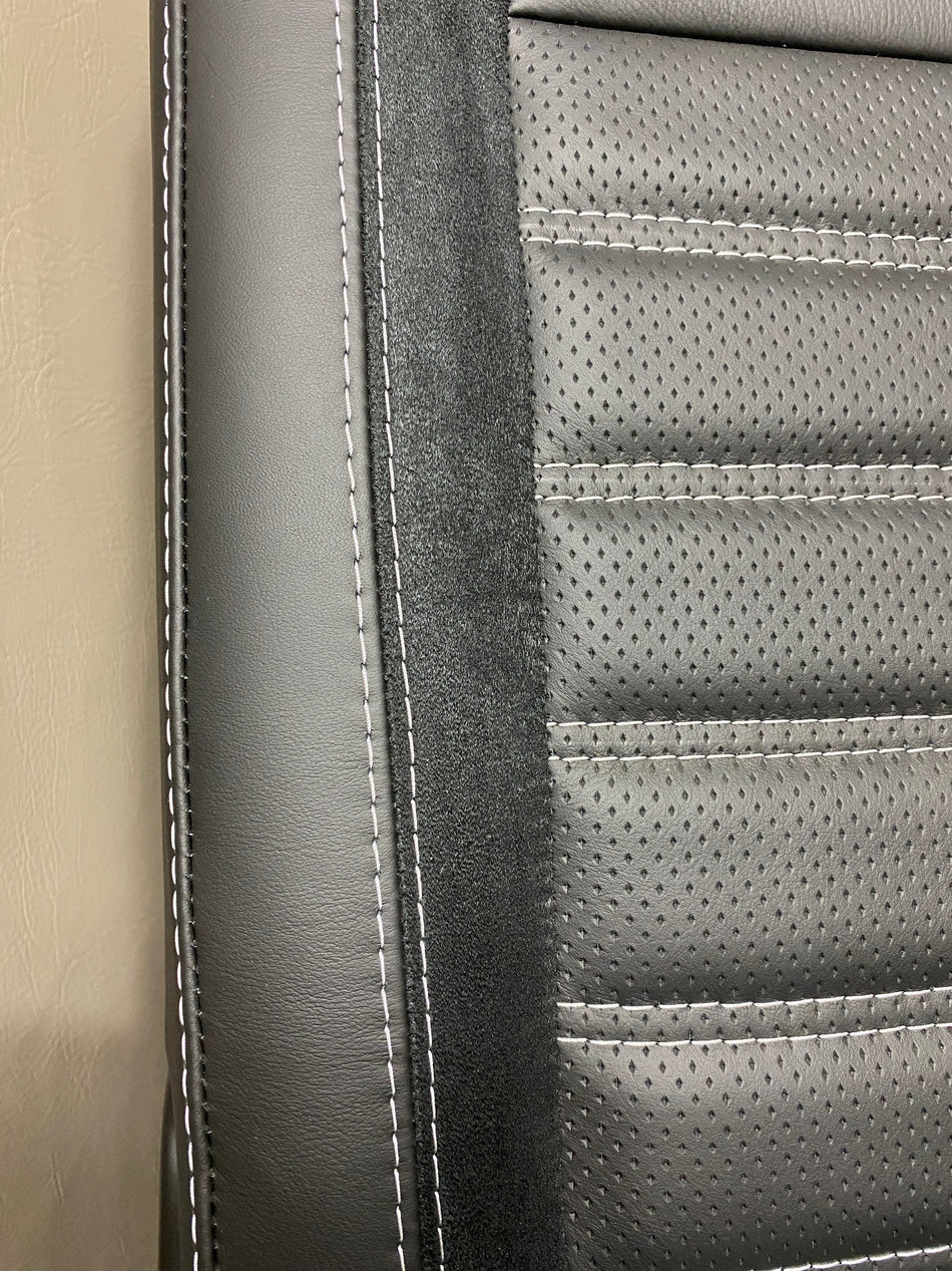 VW Factory T5 T6 seat close-up of black real leather side panel with Alcantara faux suede insert and perforated centre panel featuring black horizontal wide cross-stitching.