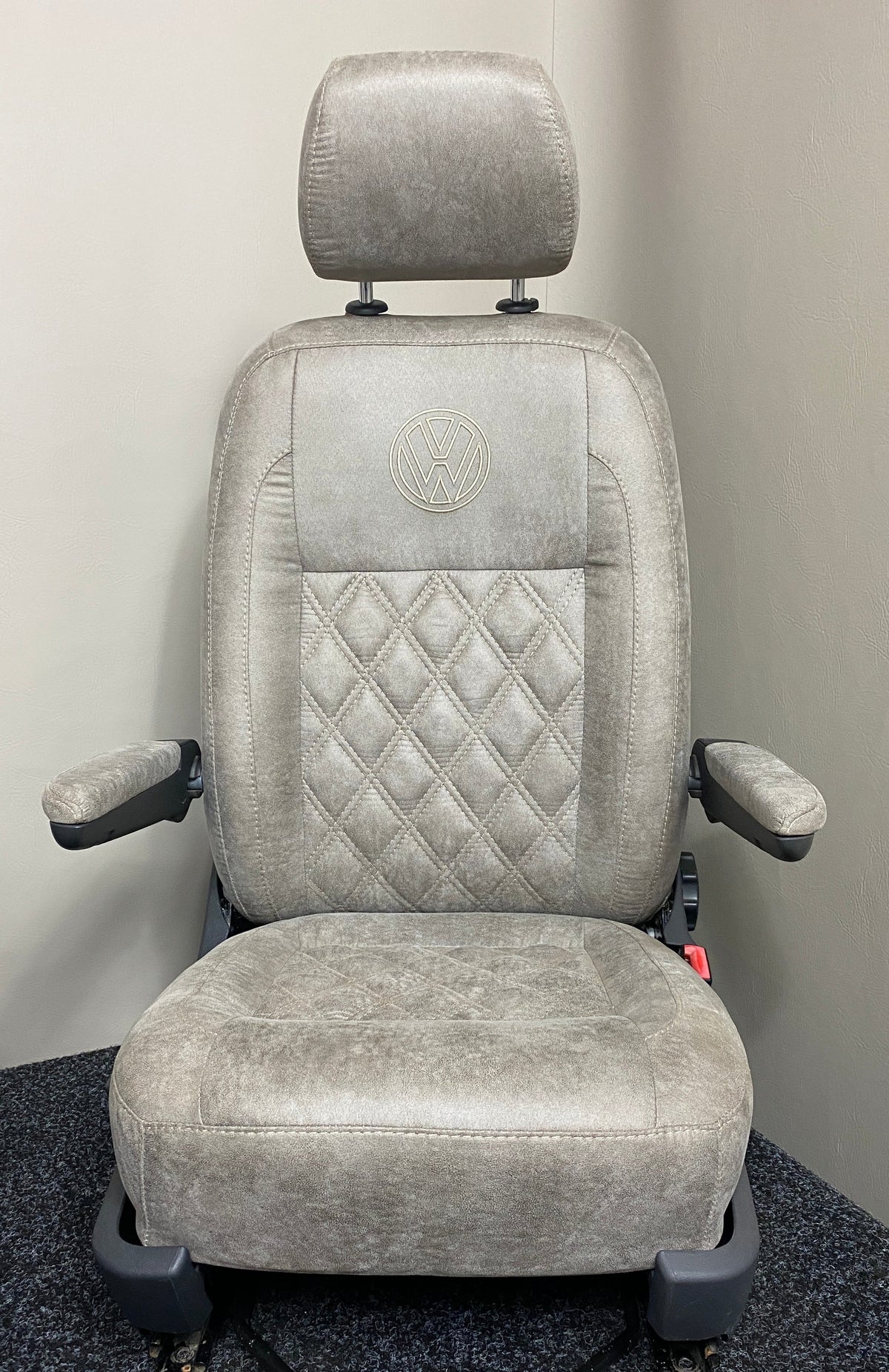 VW Factory T5 T6 Driver Seat  in beige faux suede with cream Bentley cross stitching, dual armrests, and a black VW logo on the upper backrest.