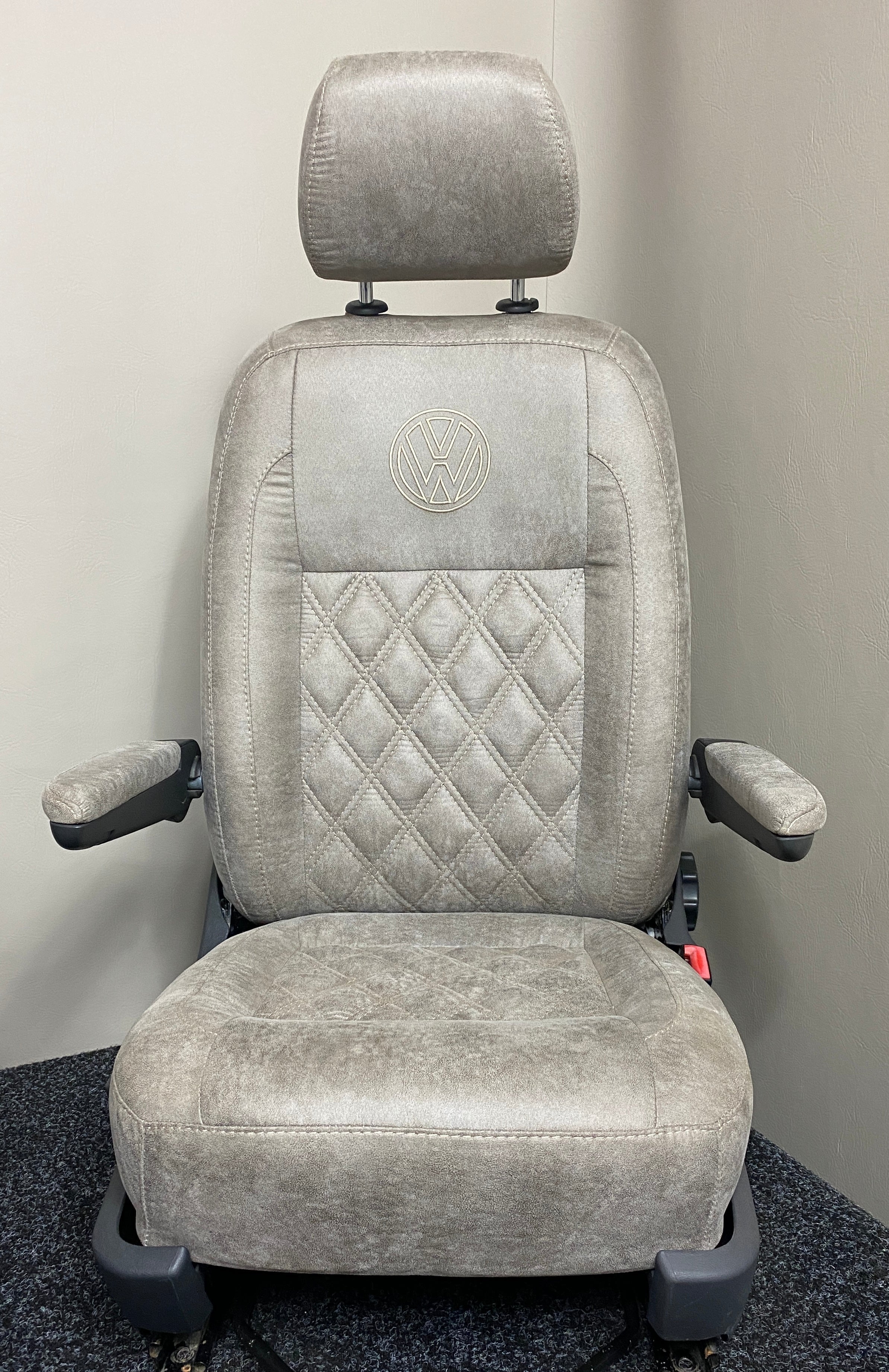 VW Factory T5 T6 Driver Seat  in beige faux suede with cream Bentley cross stitching, dual armrests, and a black VW logo on the upper backrest.
