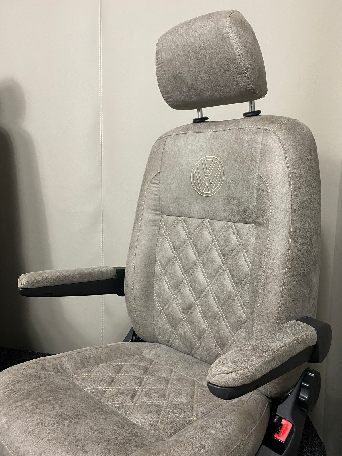 VW Factory T5 T6 Driver Seat in beige faux suede shown from a side angle, highlighting the dual armrests and diamond stitching detail.