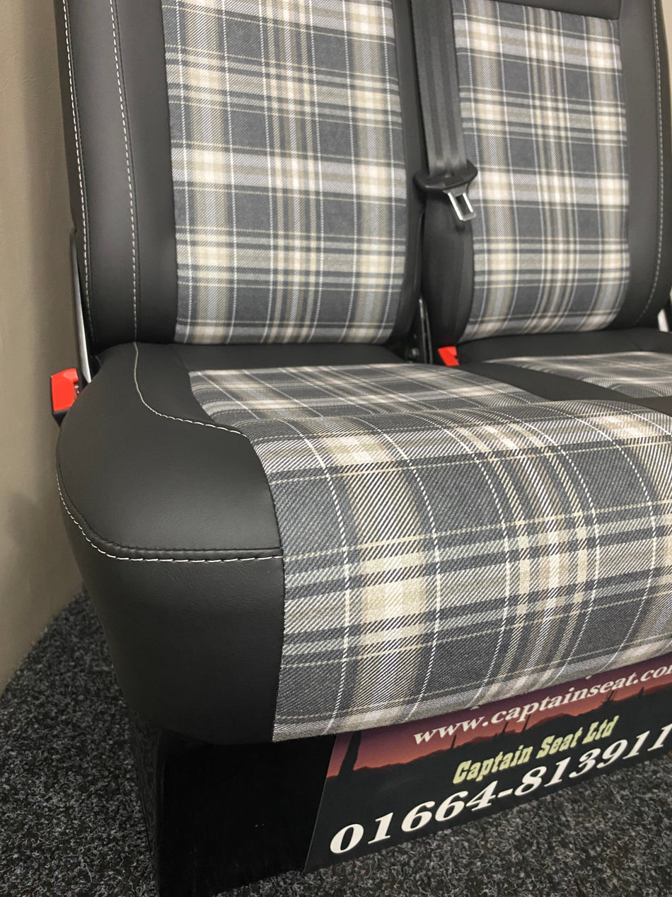 VW Factory T5 T6 Front Seat, close-up of black leatherette, light brown tartan centre panels, grey stitching, and dark grey plastic trim.