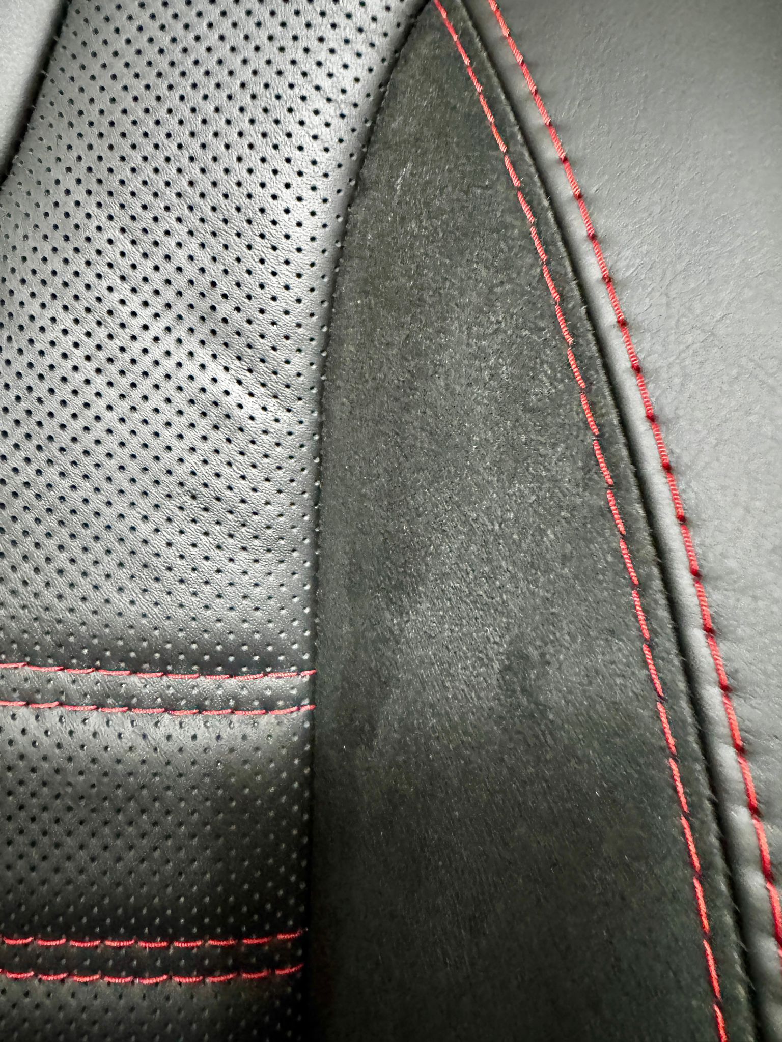 VW Factory T5 T6 Front Seat close-up of perforated centre panel and edge panel in black Nappa leather with red stitching.