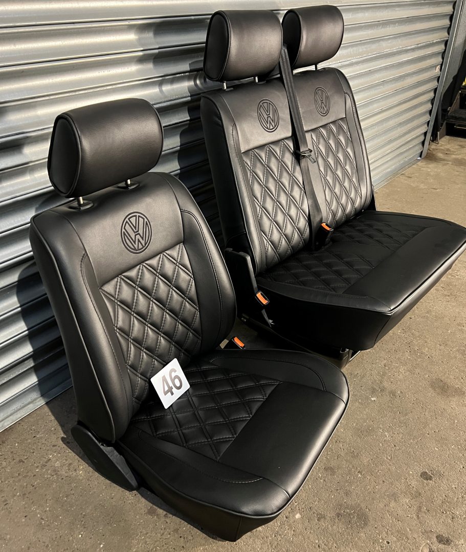 VW T4 front seats, angled view showing black leatherette finish with black Bentley stitching, VW logos, and black piping.