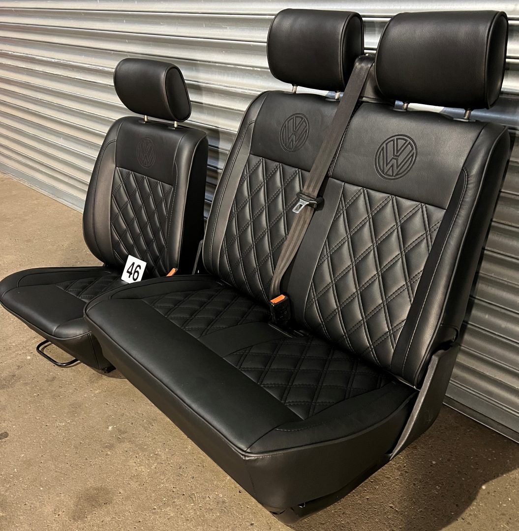 VW T4 front seats, side-angled view, showing, black leatherette, black Bentley stitch pattern, black VW logos, and seatbelt.