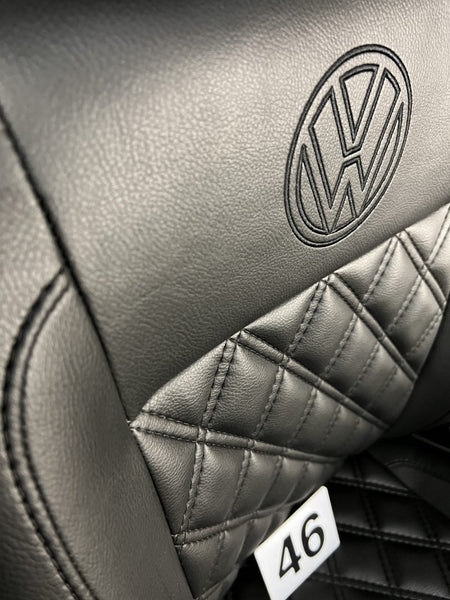 VW T4 front seats, close-up of the backrest, showing VW logo detail and black Bentley stitching on black leatherette.