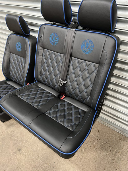 VW T5 T6 front seats, angled view, highlighting the double seat in black leatherette upholstery with blue cross stitching, piping and VW logos.